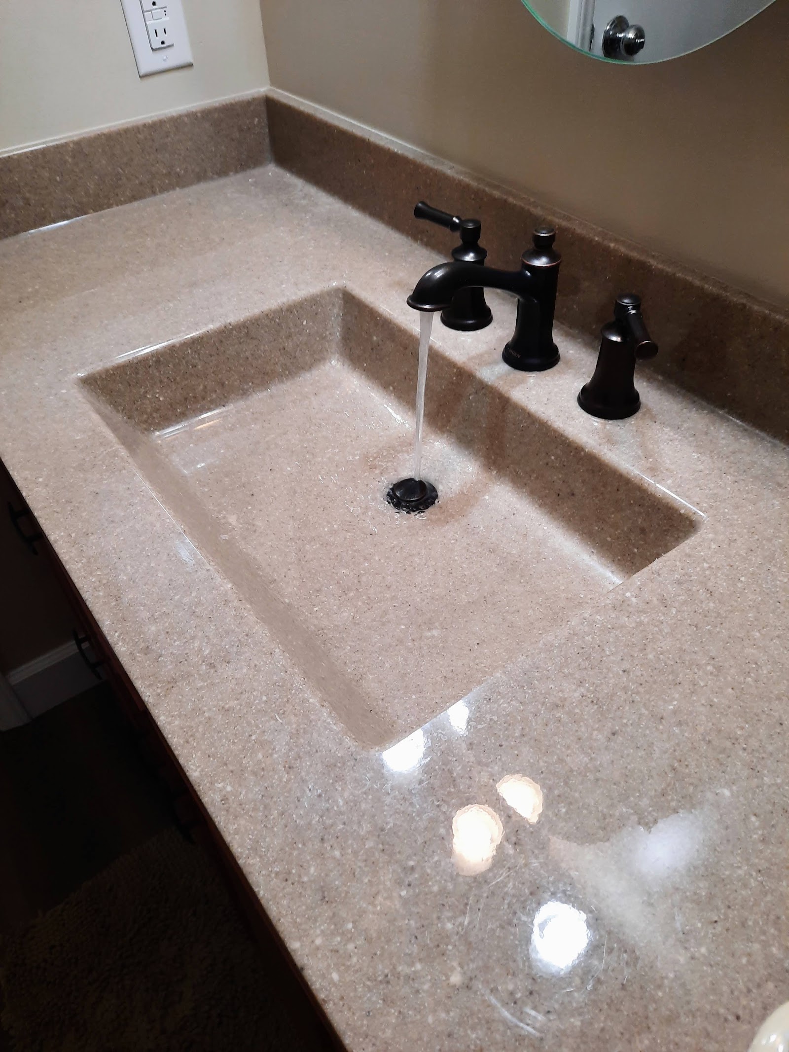 A new cultured-onyx vanity top with a seamless integrated basin and oil-rubbed-bronze faucet — no rim to trap grime.